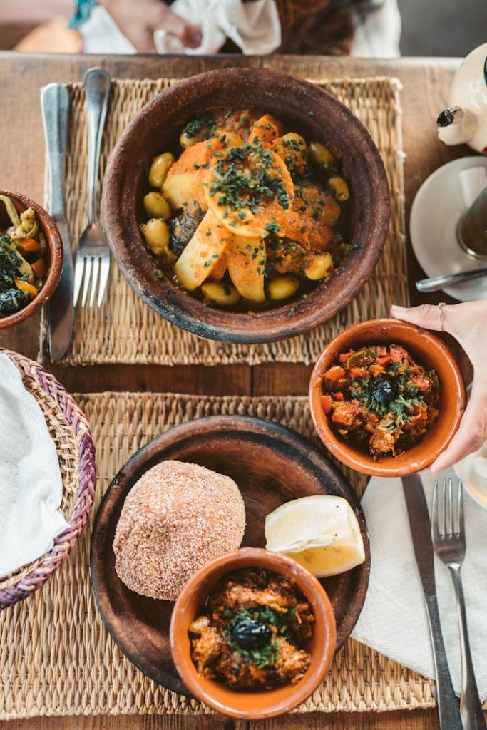 Mastering the First Impression: Your intriguing post title goes here Delicious Moroccan dishes served with fresh vegetables and traditional bread on a woven mat.