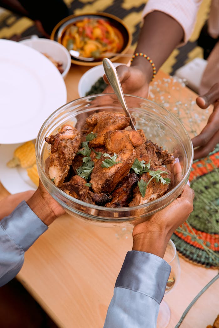 A bowl of African-style roasted meat garnished with herbs, ready to serve at a gathering.